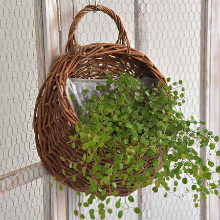Rattan Woven Flower Basket with lush green plants, ideal for adding a natural touch to home decor.