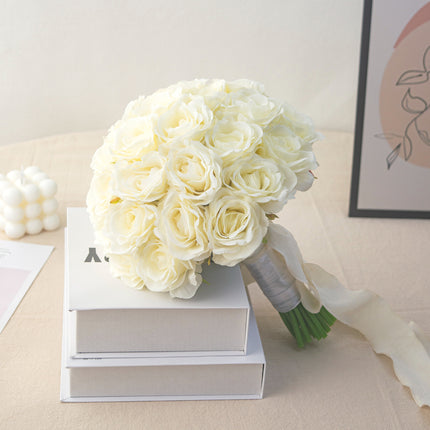 High-Quality artificial cream white silk rose bridal bouquet on a table with books and decor.