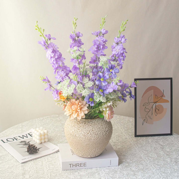 Handmade delphinium artificial flower arrangement displayed in a decorative vase on a table.