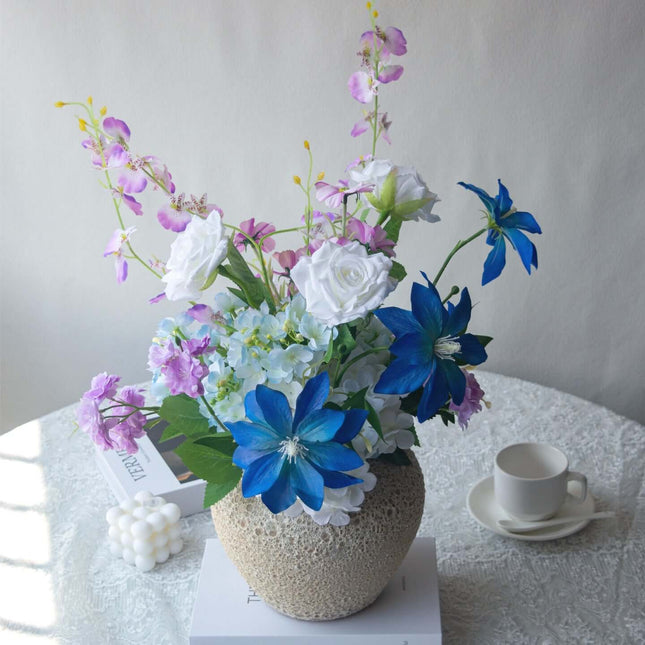 Handmade Clematis realistic artificial flower bouquet in a decorative pot on a table with a teacup.
