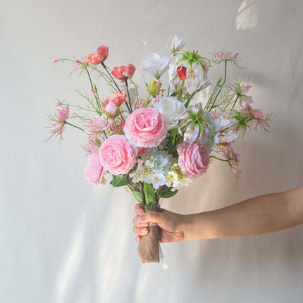 Handmade Pink-white Silk artificial flower arrangement held in hand, featuring realistic flowers and green accents.