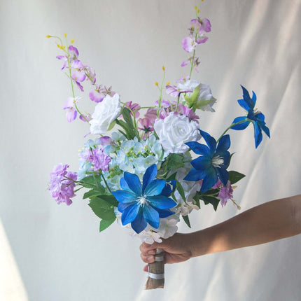 Handmade Clematis realistic artificial flower bouquet with blue and purple flowers held in a hand.